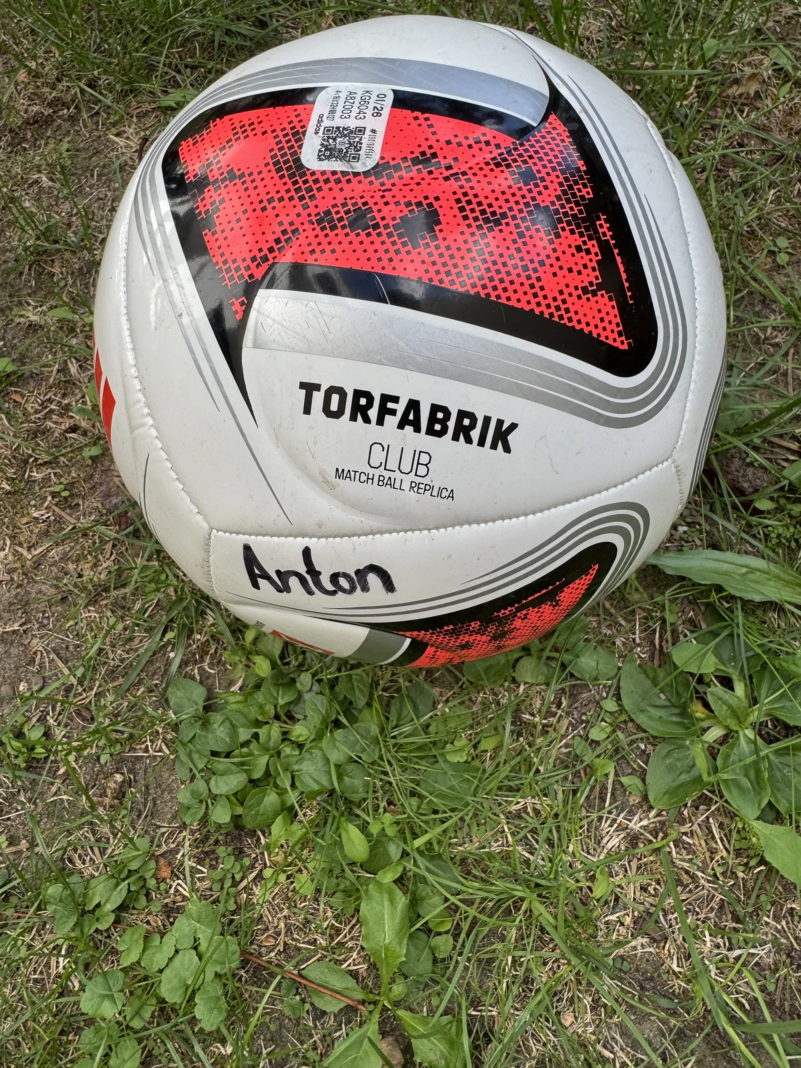 Weiß-schwarz-roter adidas Torfabrik Club auf Rasen; auf einem weißen Feld steht handschriftlich Anton.