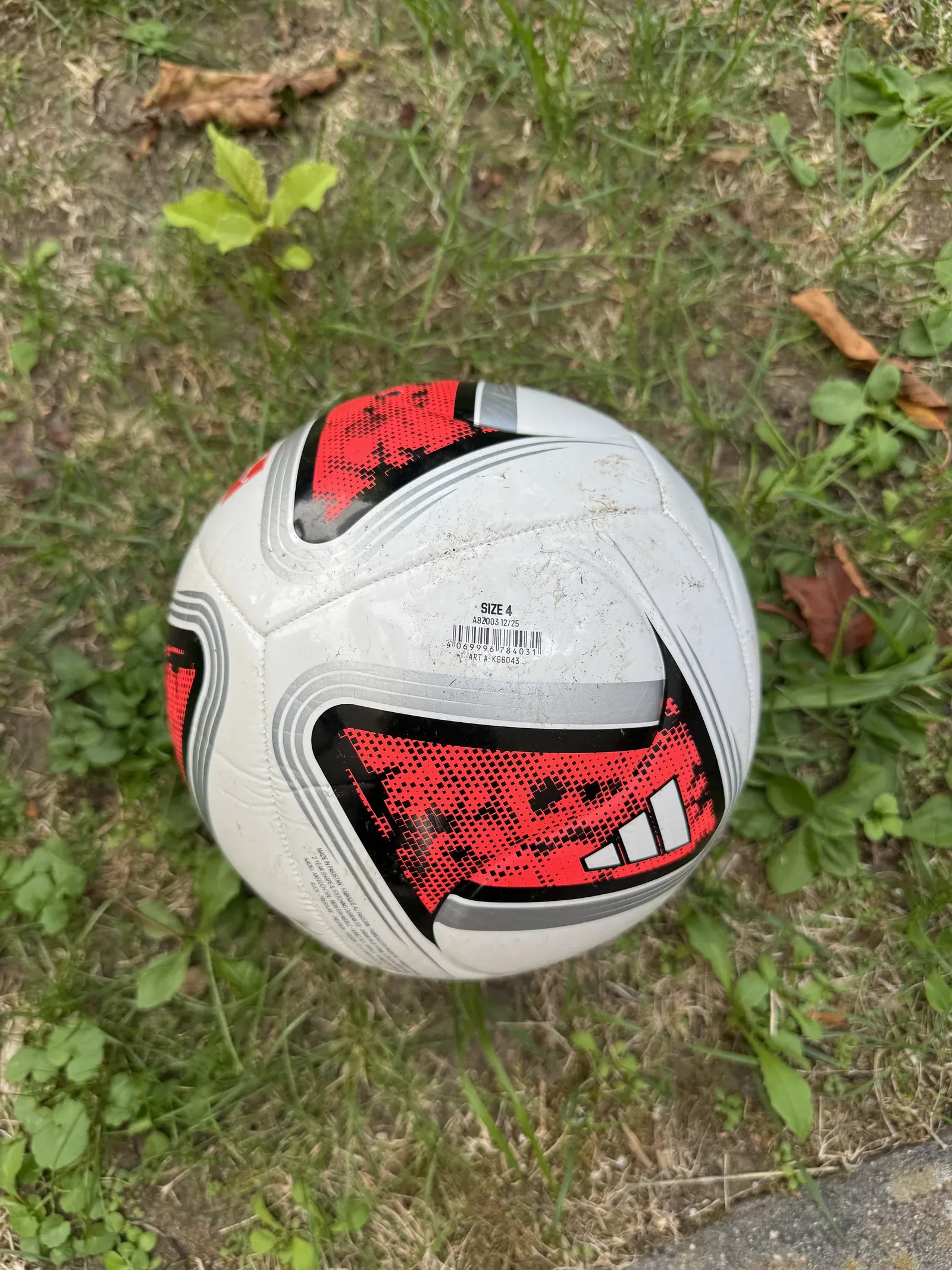 Weiß-schwarz-roter adidas Torfabrik Club von oben auf Rasen. Lesbar sind SIZE 4, ein Strichcode und die Artikelnummer KG6043.
